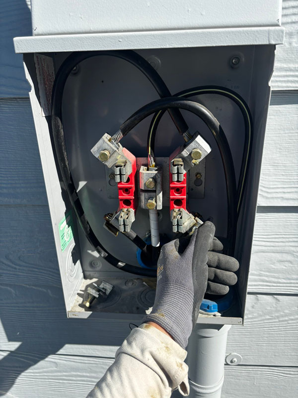 Melby Electric worker connects wires in electrical panel at house on sunny day
